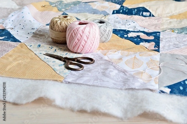 Fototapeta Hand stitch quilting process: cotton thread, needle and scissors on the table