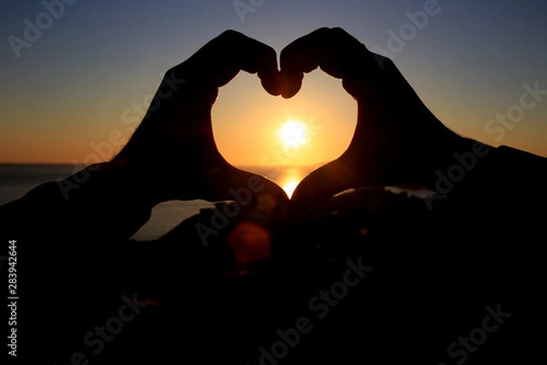 Obraz hands in the shape of a heart on the background of the sky let in the sun's rays. On the Sunset. Love concept
