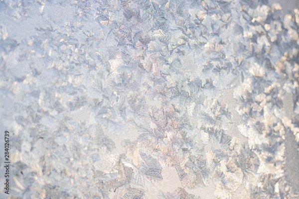 Fototapeta Ice patterns on winter glass of window, with the light seen through it. Horizontal banner. Selective focus. Creative background about winter, cold, christmas time.