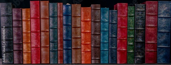 Obraz A stack of beautiful leather bound books with a black background.