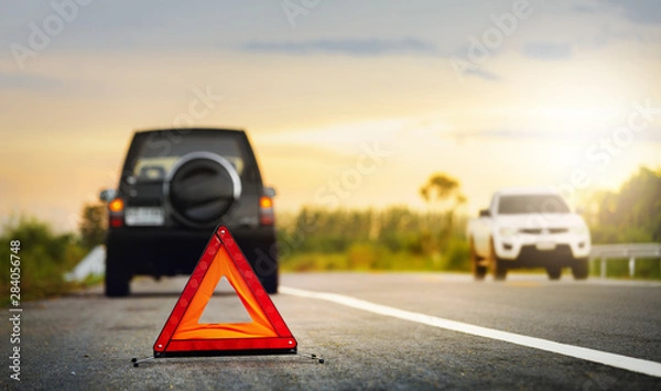 Fototapeta Red emergency stop sign (red triangle warning sign) and broken black SUV car  on country road.