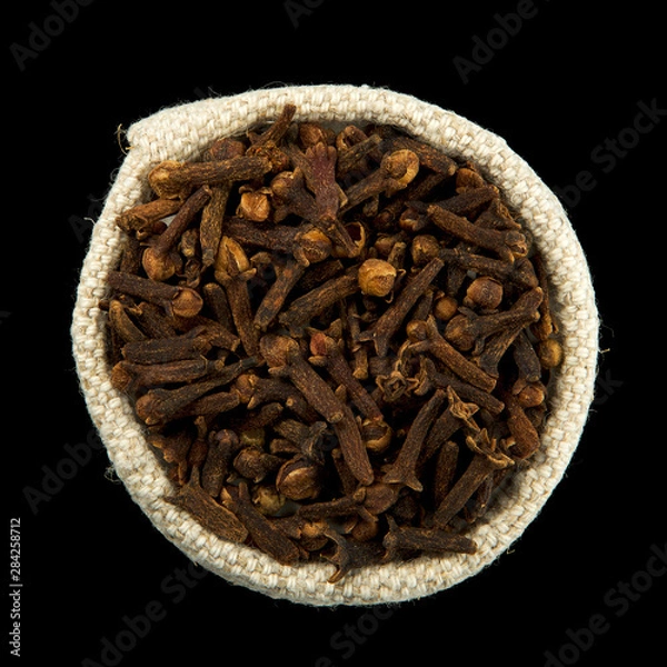 Obraz Dry cloves in a bag isolated on black background. View from above. Seasoning on isolate. Dry spices.