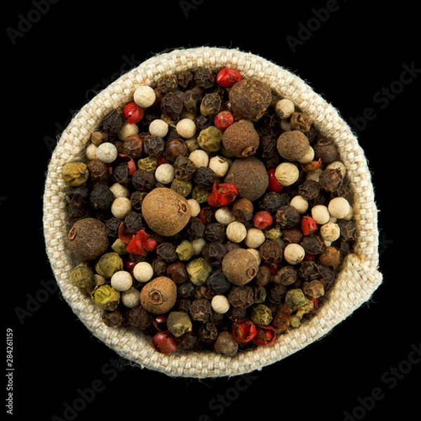 Obraz Mix of peppers in a bag isolated on a black background. View from above. Seasoning on isolate. Dry spices.