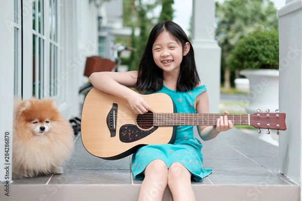Obraz Asian Child Playing Guitar with Dog