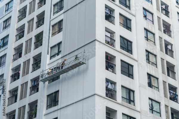 Fototapeta Apartment building with a group of worker painting building exterior