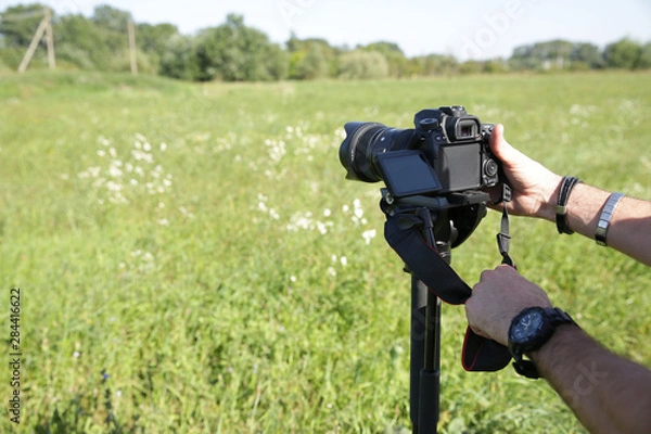 Fototapeta digital camera in hand photographer or videographer with monopod.