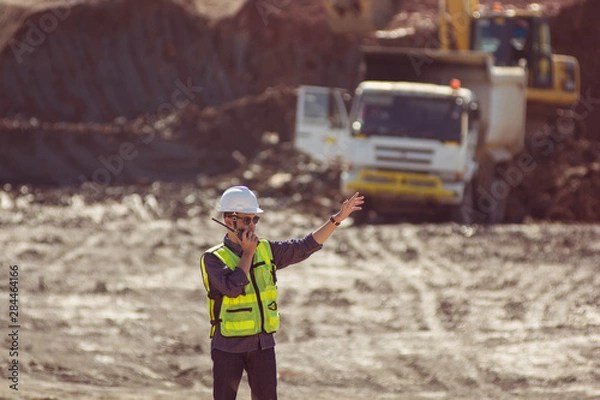 Fototapeta Portrait of asian male supervisor in mine soil field location operation a radio or walkie talkie