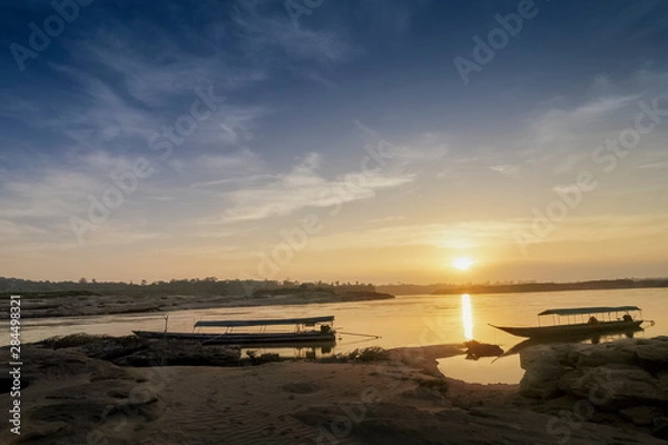 Fototapeta view morning of long boats floating in Mekong river with yellow sun light in the sky background, sunrise at Sam Phan Bok, Ubon Ratchathani, Thailand.