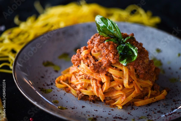 Obraz delicious italian spaghetti bolognese with minced beef sauce, tomatoes, carrots & fresh basil 