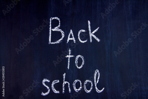 Fototapeta White chalk handwritten inscription of back to school in center of blackboard background. Preparing pupils children students for study at university, college, academy. Autumn mood concept.