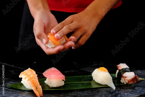 Fototapeta Closeup hands of japanese chef making sushi at restaurant