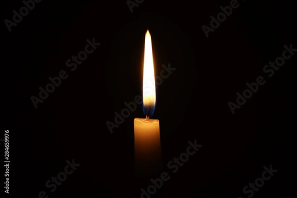 Fototapeta Burning candle in the dark with a dark background. Dark key photo.