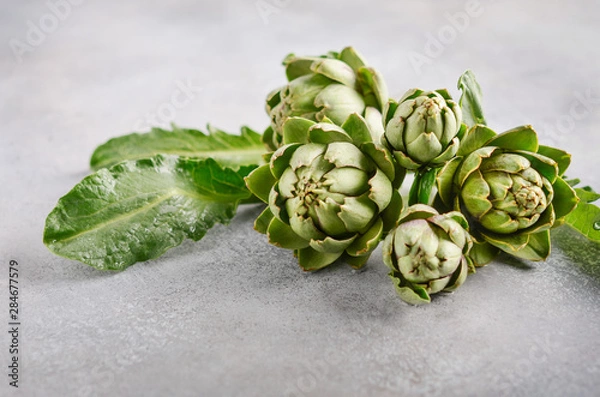 Fototapeta Fresh organic artichokes on a gray concrete background.