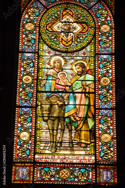 Fototapeta Montserrat, Spain, June 23, 2019: Stained glass window in the Benedictine monastery in Montserrat in Spain showing Jesus, Mary and Joseph with a donkey .