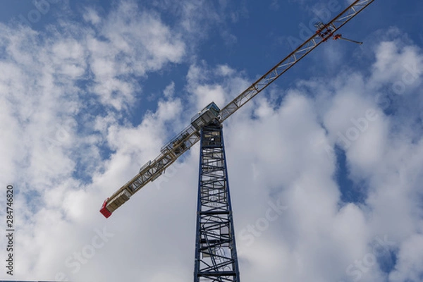 Fototapeta Low angle view under tower crane against blue sky and cloud.