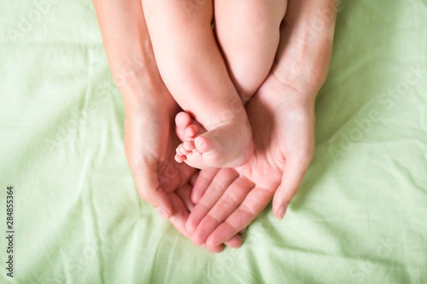 Fototapeta newborn legs in mom's hands