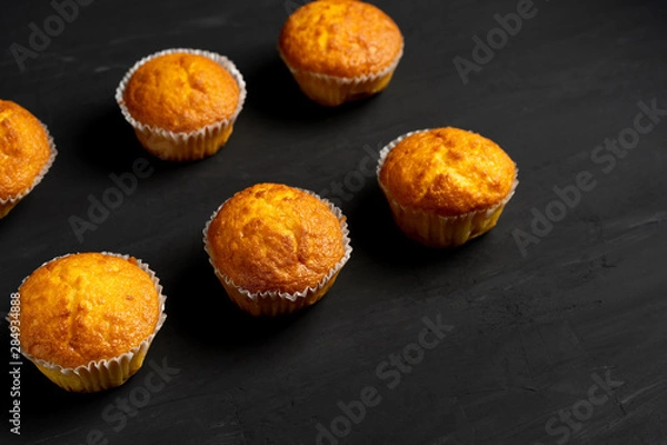 Fototapeta Appetizing muffins stand on a table top view. Traditional pastries on a dark background minimalism.