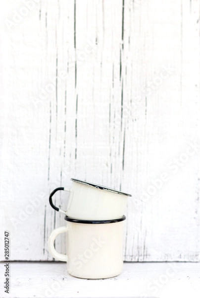 Fototapeta Enameled mugs in retro style on an old wooden background.