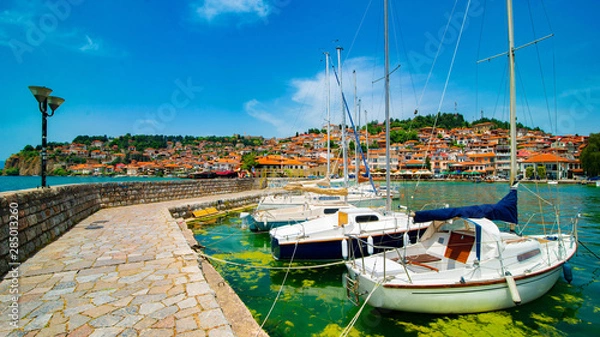 Fototapeta North macedonia. Ohrid. Different sail boats in dock on lake with buildings on hill
