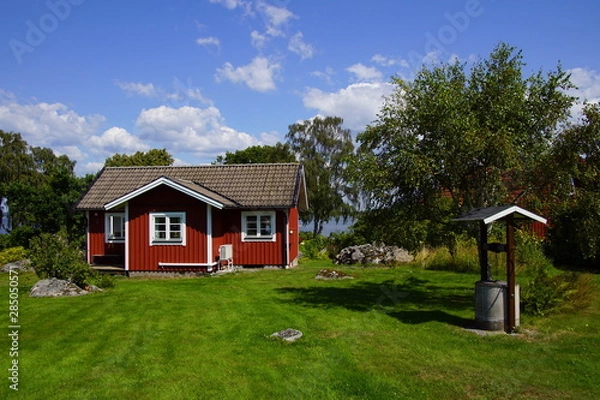 Obraz Traditional Swedish cottage in the countryside against a partly clouded blue sky.
