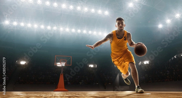 Obraz Professional basketball player dribbling. Floodlit sports arena