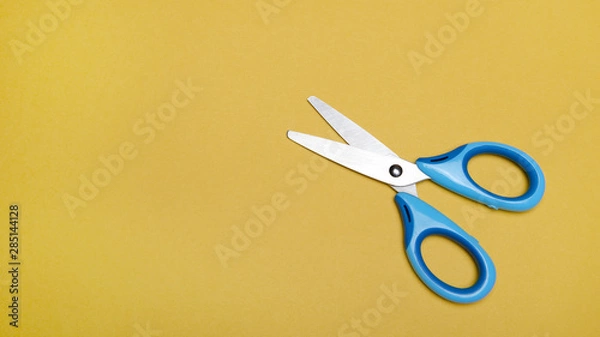 Obraz Opened blue scissors over yellow background. 