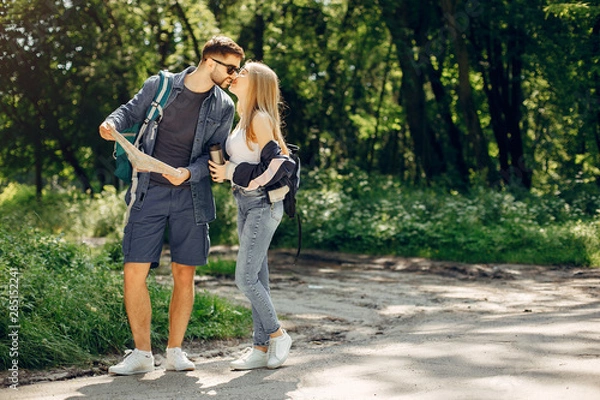 Fototapeta Tourists in a summer forest. Couple with a map.