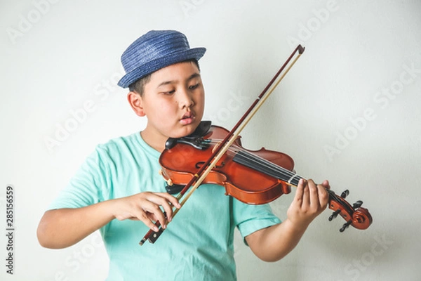 Fototapeta Asian children are playing violin instruments in the classroom.