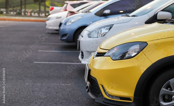 Fototapeta Closeup of front side of yellow car and other cars parking in parking area after raining. 