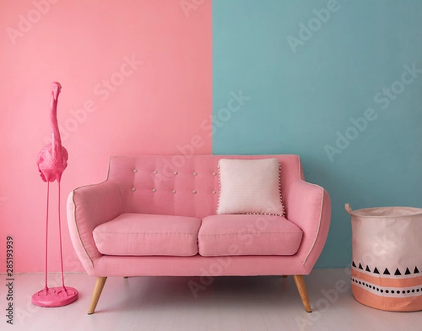 Obraz The pink sofa which has a white pillow is set in living room which has blue and pink wall.