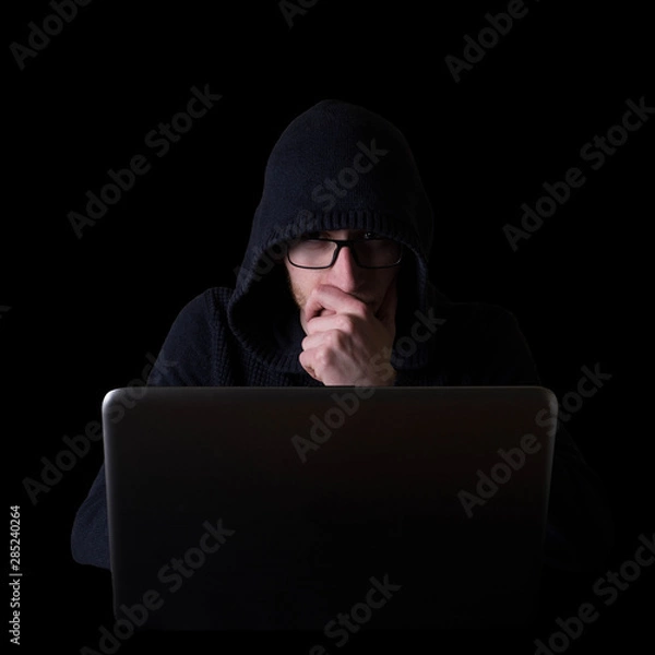 Fototapeta Hacker,programmer on glases in front of his computer, with laptop initiating cyber attack, isolated on black backgroung