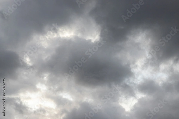 Fototapeta Dark heavy clouds. Rain clouds. Time before the rain. There are bright gaps behind the clouds. Background with free space and empty place.