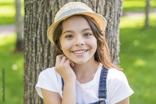 Fototapeta Smiley little girl posing in front of a tree