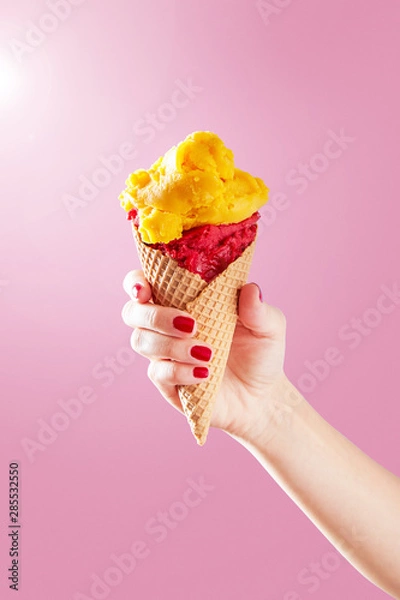 Fototapeta Woman hand holding ice cream cone on a pink background. Copy space