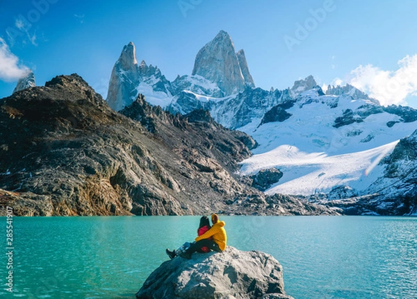 Fototapeta Couple in love at Mount Fitzroy. Scenic view of snowcapped mountain tops of Patagonia trek. Blue sky, turquoise lake and scenic rock landscape. Shot in Argentina. Nature, travel, adventure, hiking.