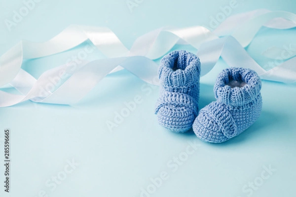 Fototapeta Niebieskie buty z dzianiny dla noworodków na niebieskim tle, minimalne chrzciny, tło imprezy noworodka, miejsce na kopię