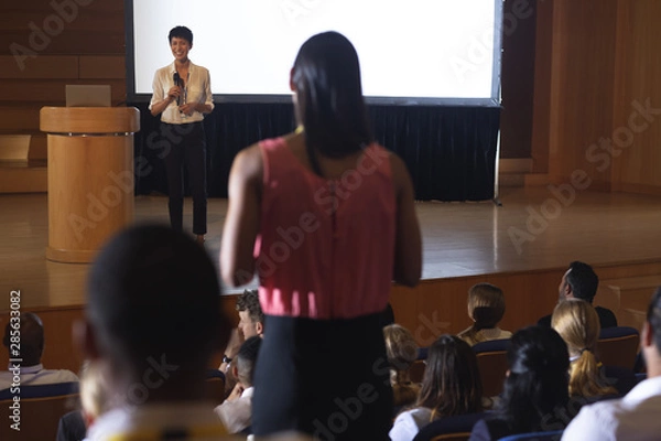 Fototapeta Woman from the audience standing and asking query in the auditorium 