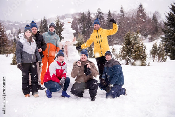 Obraz group portait of young people posing with snowman