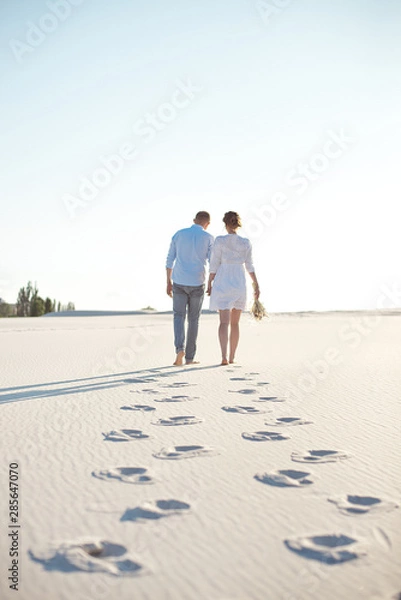 Obraz Happy couple walking holding hands at the beach