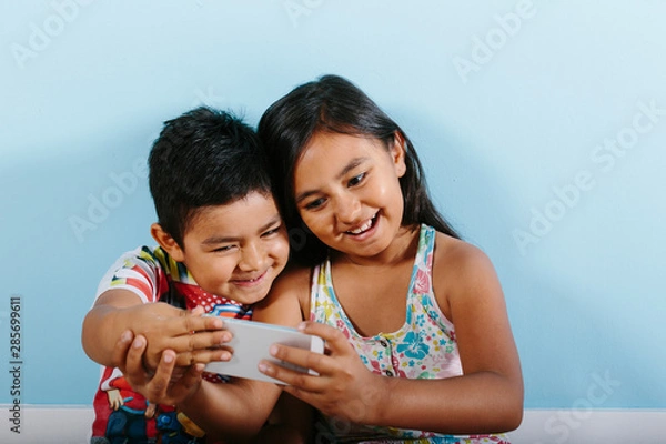 Obraz Two kids taking a selfie over blue background