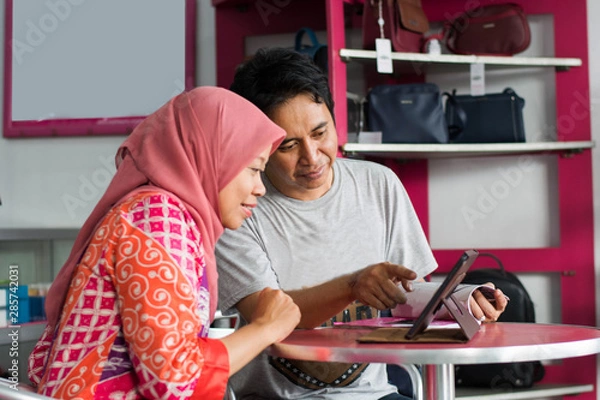 Obraz Portrait of Asian muslim middle age husband and wife discuss about business in their store