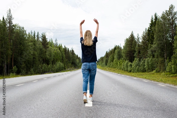 Obraz Girl walking on an empty road. New way. Forward movement to the future. Casual look. Enjoy the moment, relaxation. Lonely beautiful women. Wanderlust. Travel, adventure, lifestyle. Explore Finland 