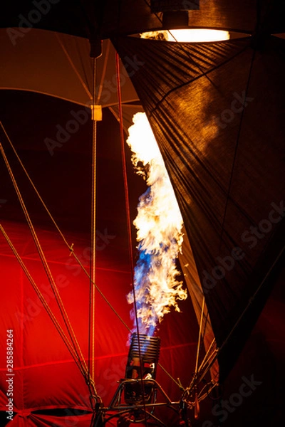 Fototapeta The burners on a hot air balloon firing up, sending a burst of ignited gas  in balloons festival night