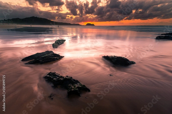 Fototapeta Light reflections at Zarautz beach with the mouse of Getaria at the bottom in a summer sunset.