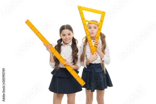Fototapeta Our favorite lesson. Little girls preparing for geometry lesson. Cute schoolgirls holding triangular and ruler for lesson. Small children with measuring instruments at school lesson