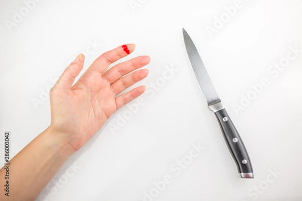 Fototapeta Accident wounded finger with blood and kitchen knife. Injured left hand finger with bleeding open cut on a white background