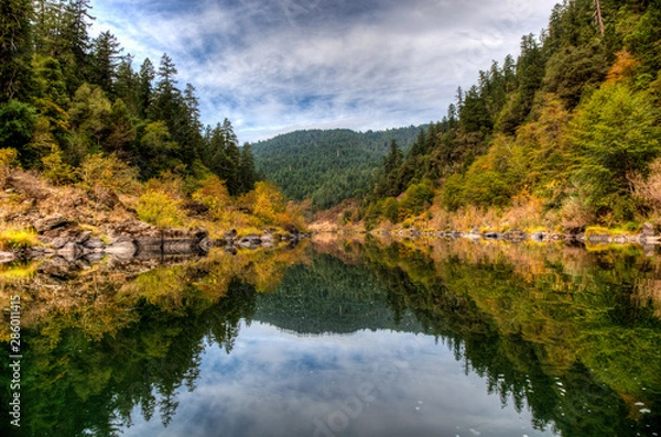 Fototapeta Orange and yellow fall colors reflect in the Rogue River on a calm section in the afternoon