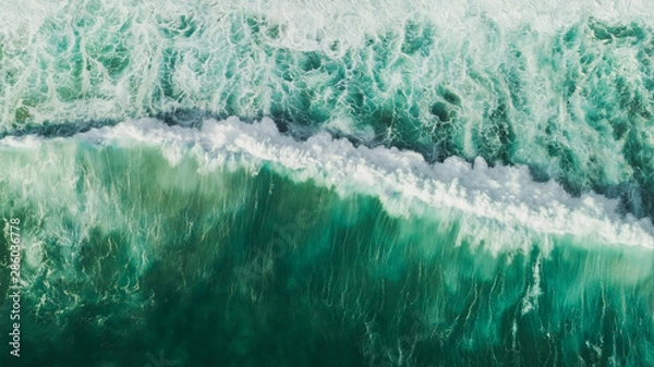 Fototapeta Aerial wave background. Drone shot directly from above, green turquoise color, huge waves. Empty space