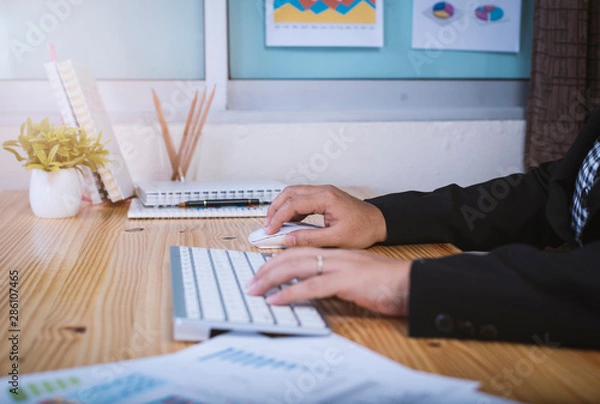 Fototapeta Closeup asian businessshot of female hand holding mouse and working with desktop computer at home office.Working serious concept.