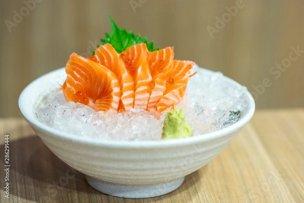 Obraz A delicious famous traditional Japanese food name Salmon sashimi sliced and served with wasabi paste on crushed ice in white bowl in Japan restaurant. Closed up with show texture. Front view.